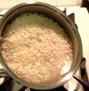 Rice almost cooked in a saucepan on the stovetop