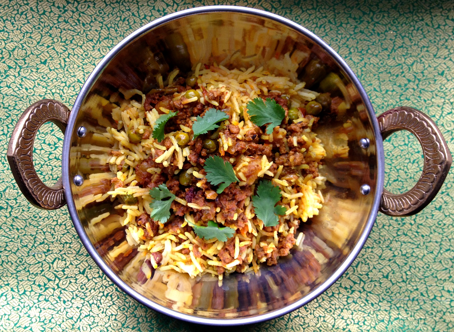 Lamb Keema in a copper bowl on green and gold tablecloth
