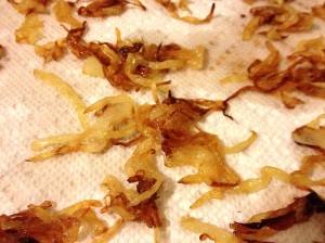 Browned onions on a paper towel-lined platter for Lamb Biryani