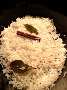 Layering lamb biryani starting with basmati rice