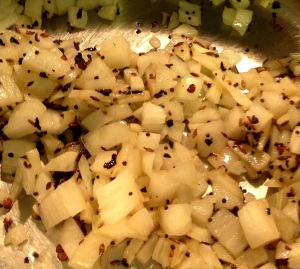 Adding onions and garlic to oil for oven-roasted eggplant raita