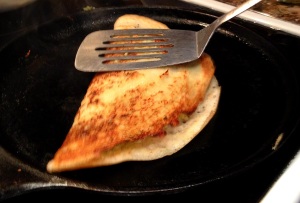 Gently pressing down on masala dosa with spatula